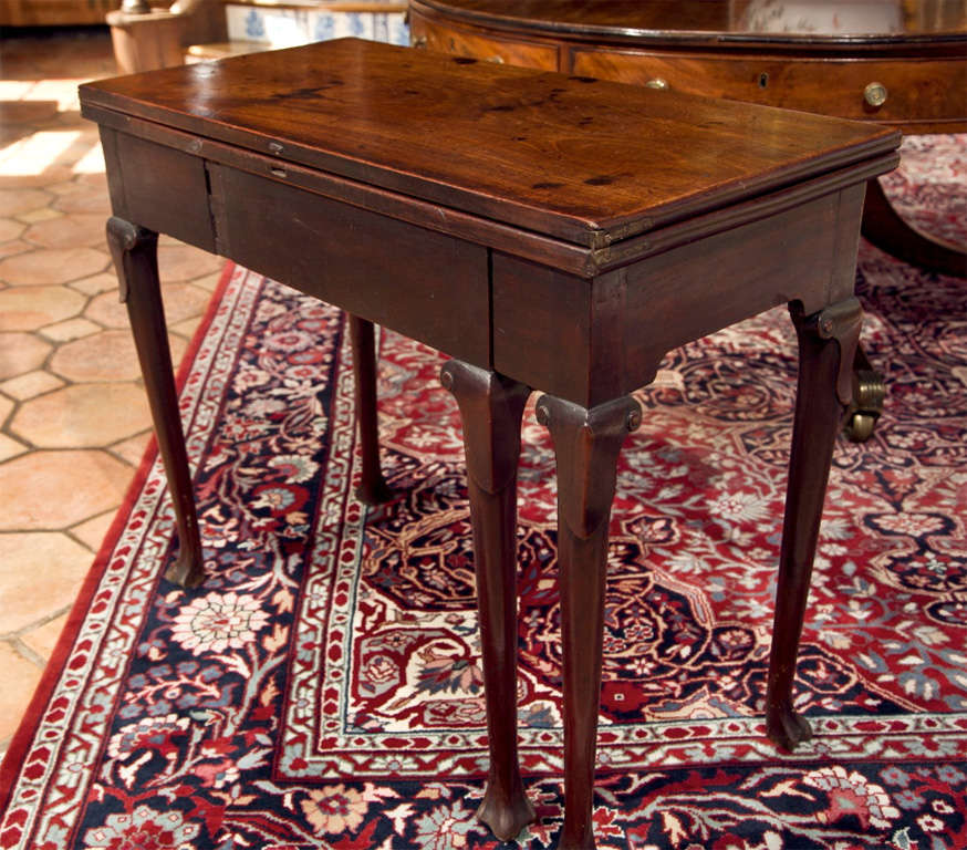Constructed of solid mahogany, this flip-top tea table features a unique scrolled knee and trifid foot. Beautifully grained and bearing a rich, warm patina, this table would serve well as a console in a hall or as its intended purpose of hosting tea.