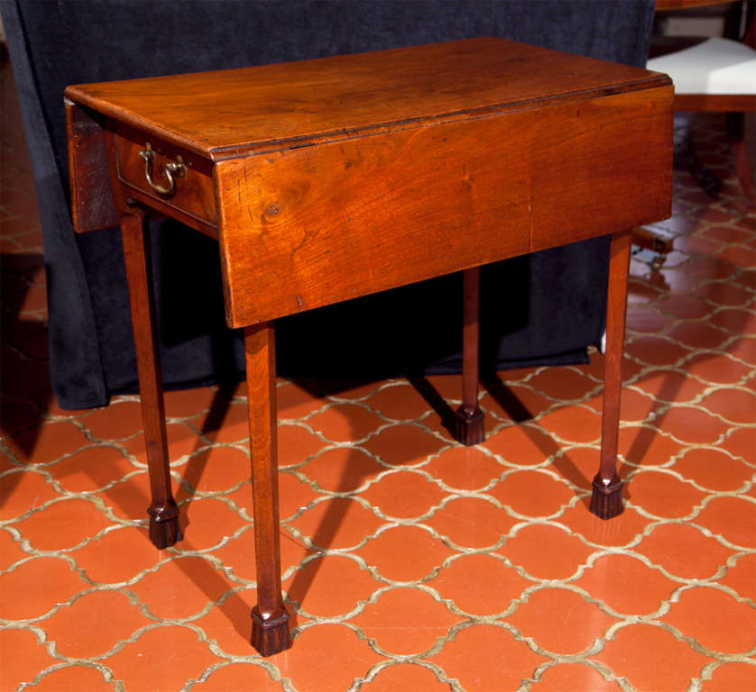 This mahogany Pembroke has a set of legs that, rather than looking like they are supporting the piece, have the appearance of hanging from the bottom of the table and terminating in tassels. By breaking the normal plane of the angle on the legs by