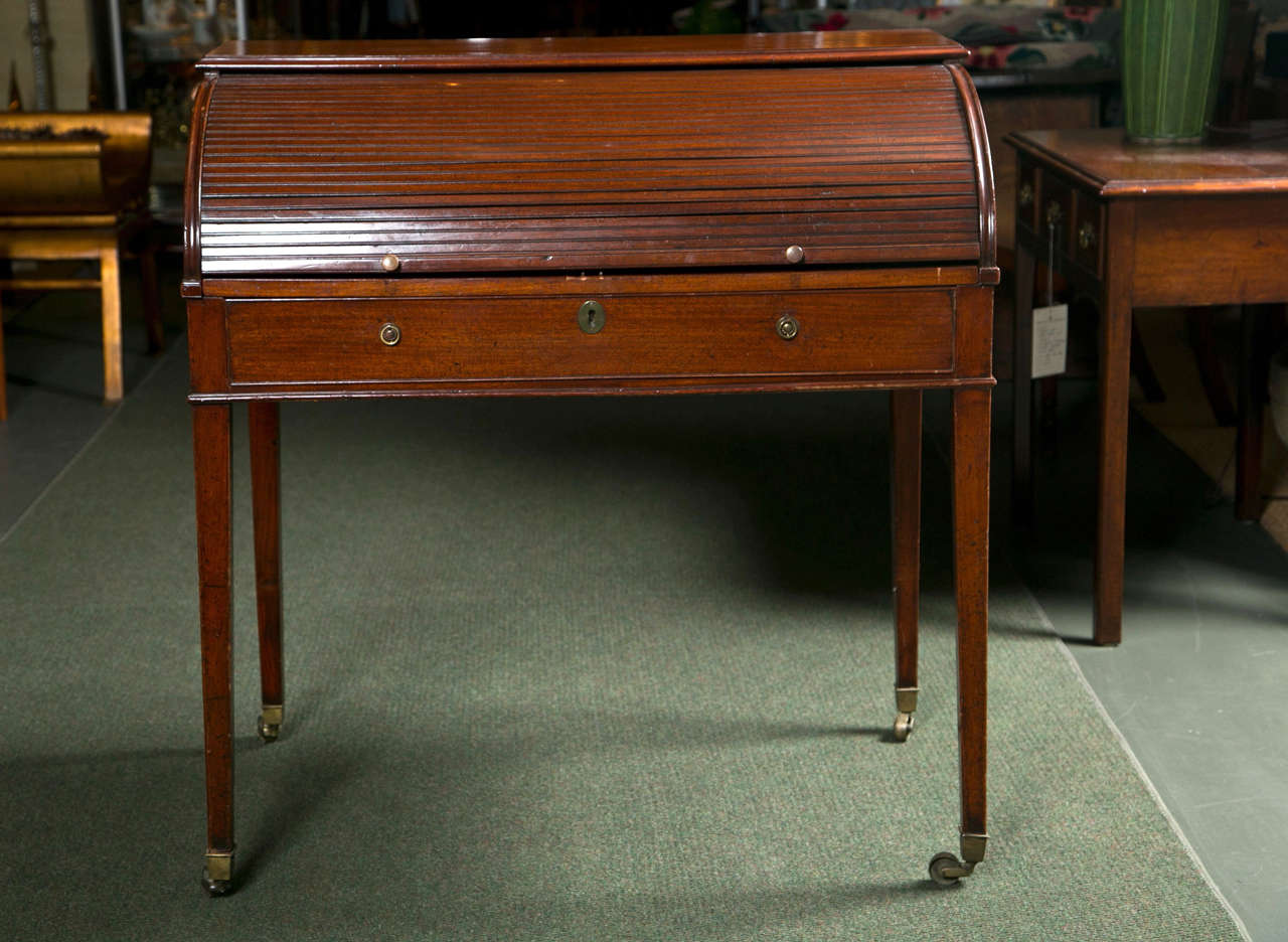 An English Sheraton mahogany, tambour or roll top desk, fitted with compartments and slide-out leather-embossed writing platform.