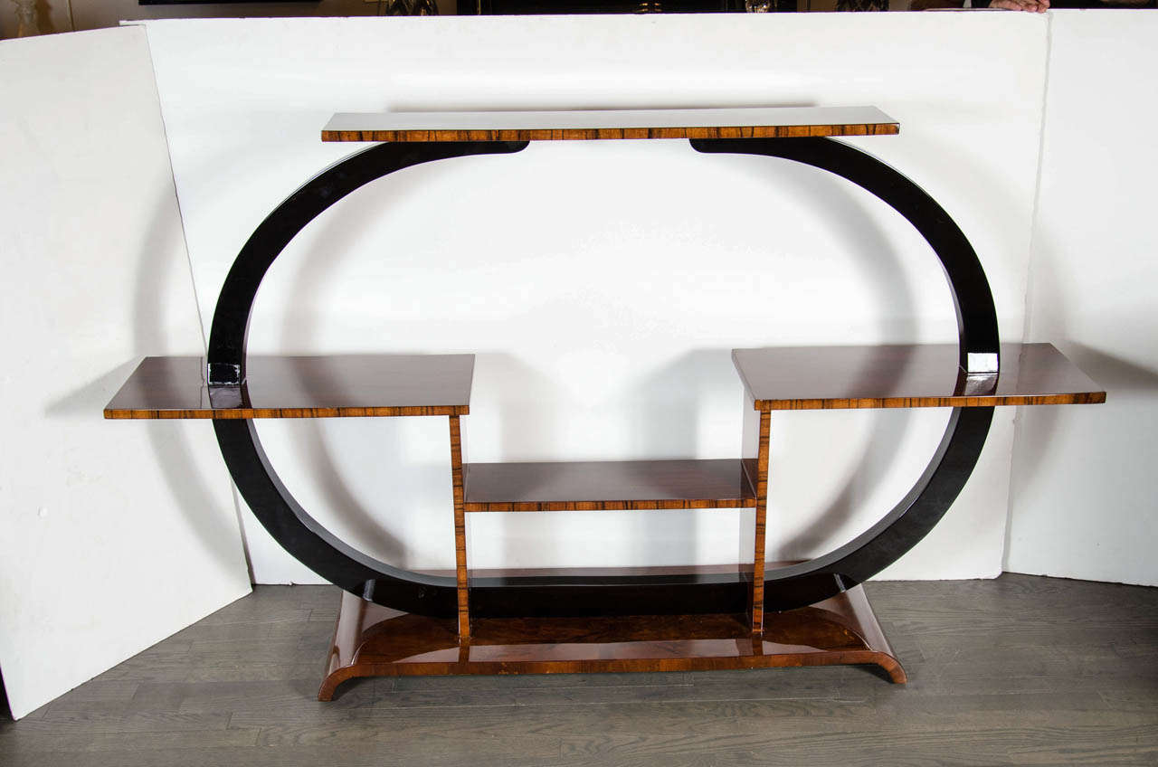 Exquisite Art Deco Etagere in a spectacular and unique shape.  It has an oval shaped surround in black lacquer which supports numerous shelves in an exquisite array of book-matched Walnut.  Starting with its scroll base, the black lacquer oval