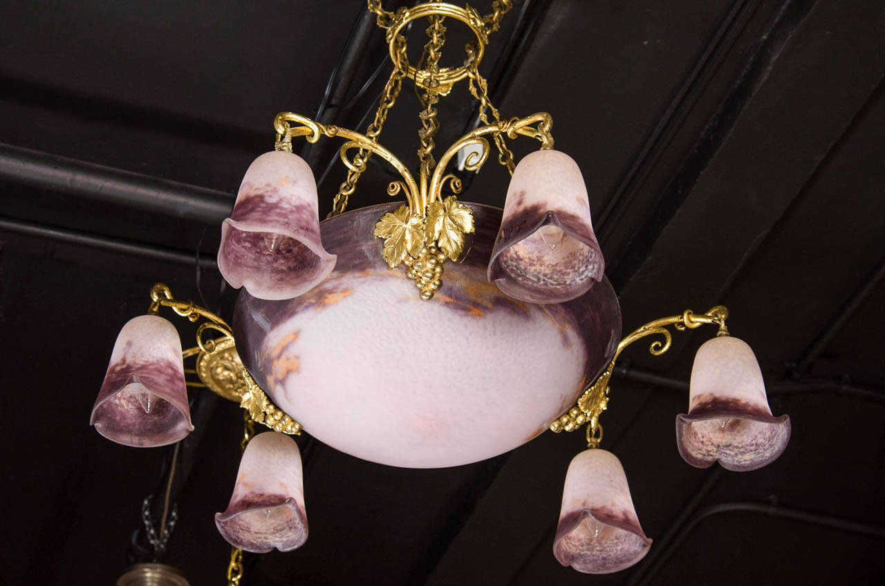 This is an exquisite and rare chandelier by the French master Degué in a nature theme. The glass has a beautiful shade of aubergine on a bed of mottled white and around the bowl the chandelier has three arms with six down lights with tulip shades.