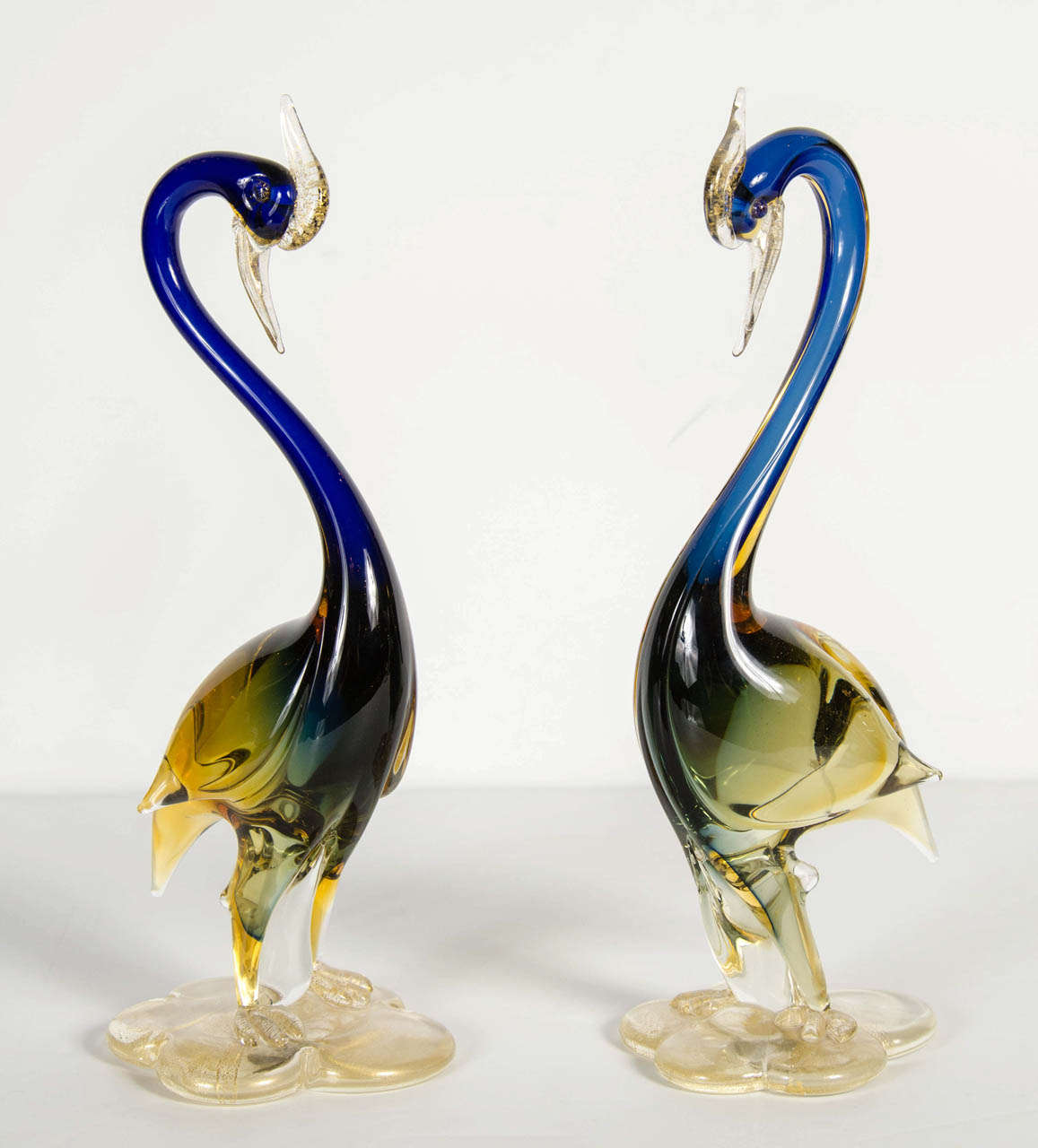 These gorgeous hand blown Murano glass cranes feature a sapphire blue body with amber accents on a base with flecks of 24k yellow gold in clear glass.Stunning accent pieces.