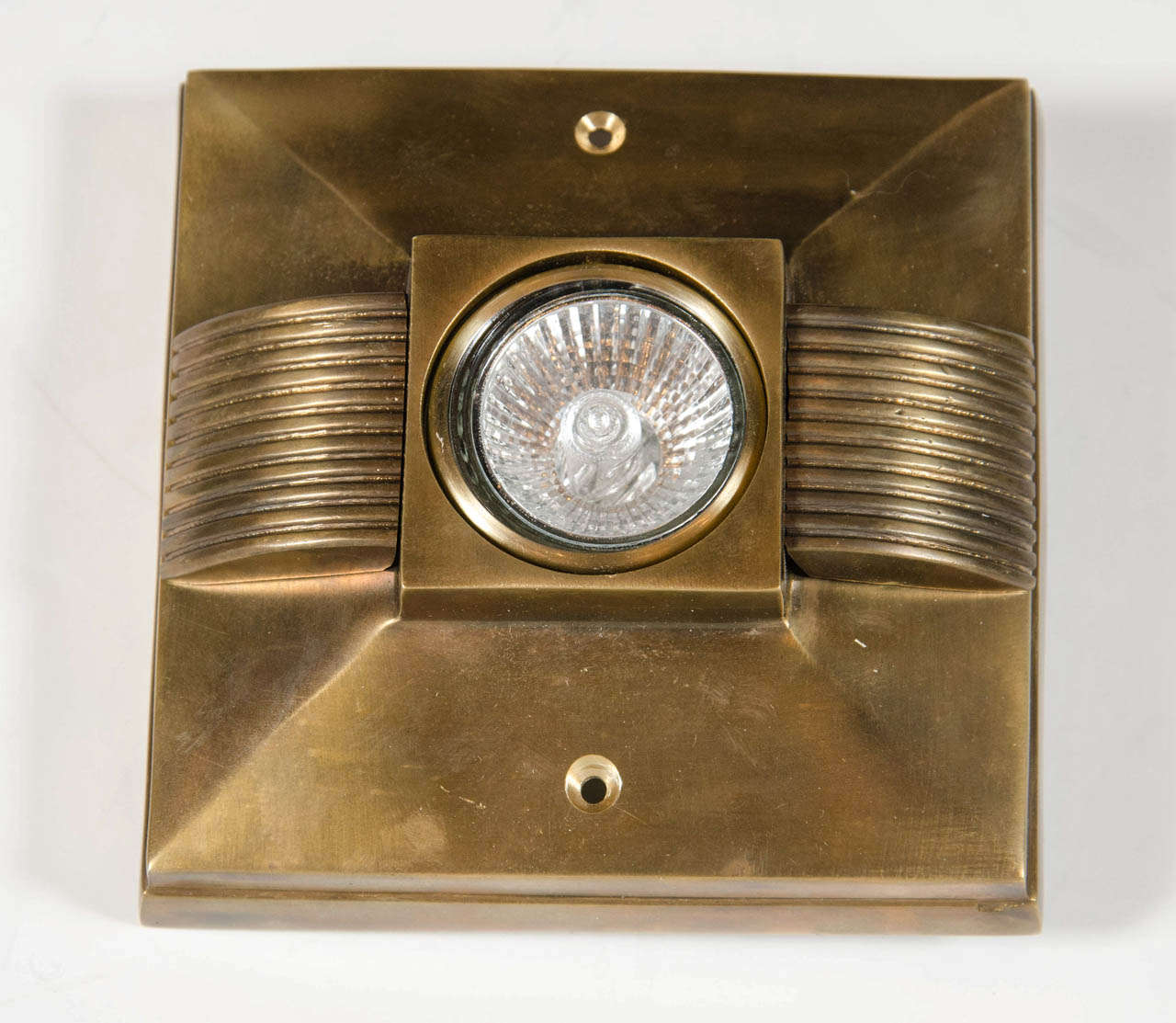 This patinated bronze spotlight features a Art Deco ribbed detailing in a shadow box surround.