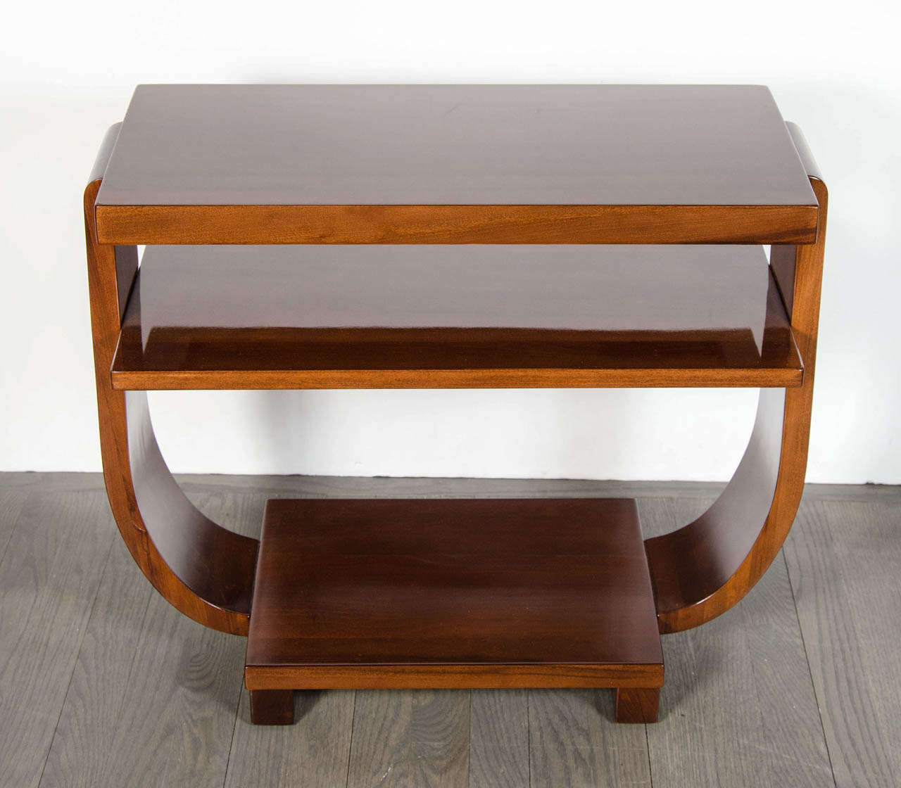 Art Deco book-matched Walnut side table with two-tiers, concave bentwood supports and a lower shelf.  This beautiful table is a great example of the streamline Art Deco movement in America.  It has been completely restored to mint condition.