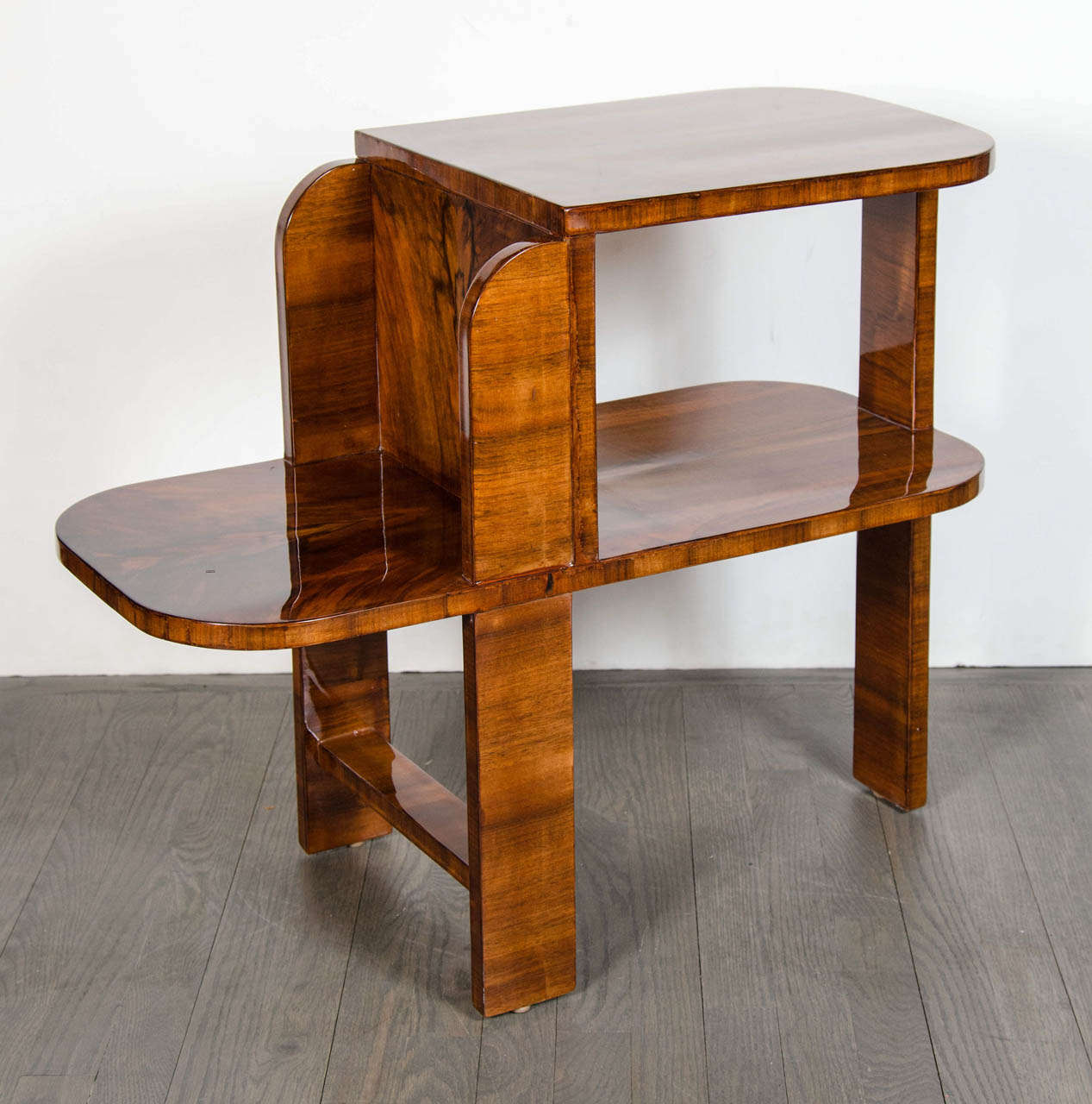Art Deco Machine Age side table in exotic burled Walnut.  This great occasional table with a bullet shaped design has a stacked, two-tiered design on one side with an exposed bottom tier shelf for more surface space.  It has an open design which