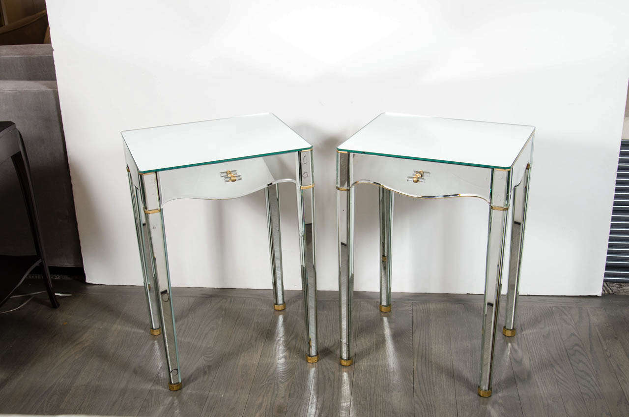 Pair of Art Deco Directoire Style Mirrored Nightstands / End Table features a beveled and scalloped mirrored pull out drawer , gilt mountings with  glass rod pull. Both tables have front drawers and one table has a hidden side drawer for