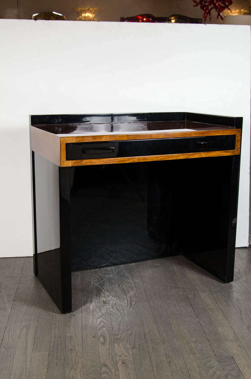Art Deco Machine Age writing table / vanity by Modernage.  It features one drawer with a black lacquer drawer front and an exceptional surround and desk top in burled Elm.  The sides on this piece are in black lacquer giving the entire piece its