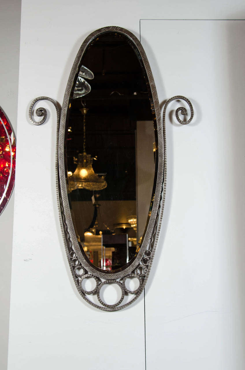 This elegant beveled wall mirror features a hand wrought iron frame in an elongated oval design and graceful circular and scroll decorations.Great for a powder room.