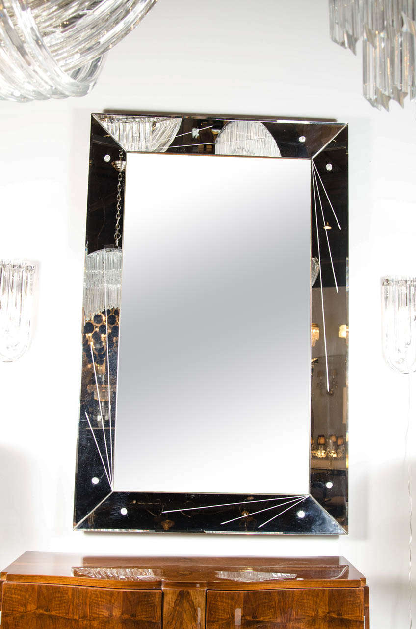 This sophisticated Art Deco beveled mirror features a mirrored border with a fine geometric design of lines that radiate from its corners. It also features a shadowbox design with rosette detailing. This mirror can be hung vertically or horizontally.