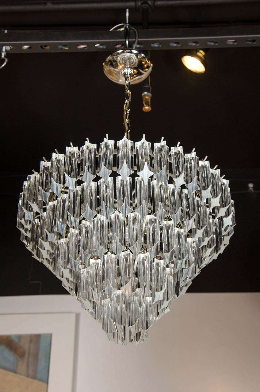 This exceptional mid-century chandelier by Venini features individually hand made Murano glass triedre prism rods that are cut at an angle individually hung from its chrome frame in a cascading effect for a five tiered tapered circular design. The