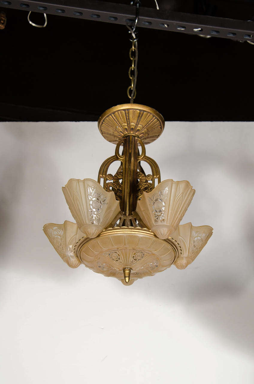 This gorgeous Art Deco chandelier by the Lincoln Lighting Co. is made of gilt wrought iron with frosted amber glass shades & stylized Art Deco geometric detailing. This has been completely rewired to American standards. Excellent condition.