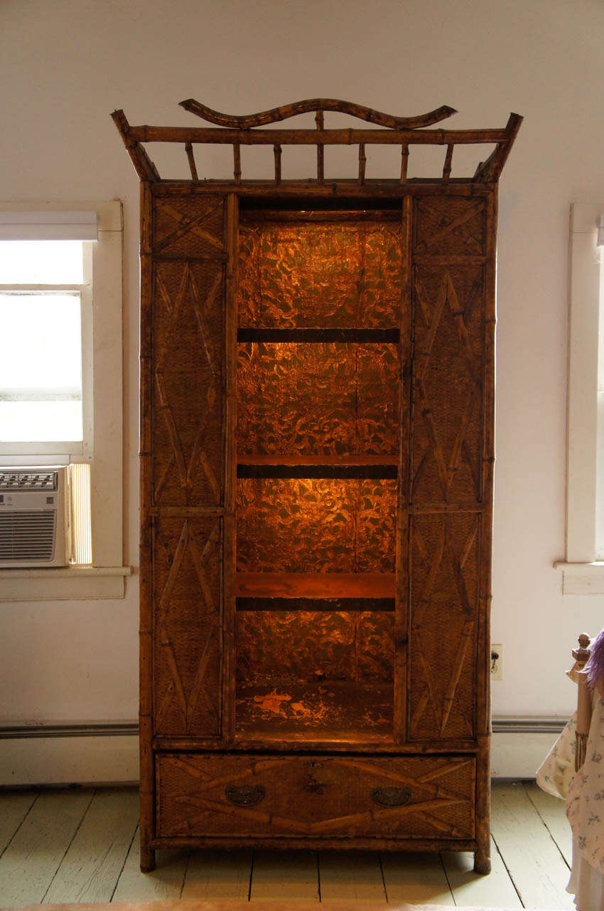 Handsome Victorian bamboo and seagrass covered armoire with (three) open
shelves and lined in lincrusta paper. Interior lighting. One drawer with
brass pulls. Transformer for lighting in the drawer connected with wiring.