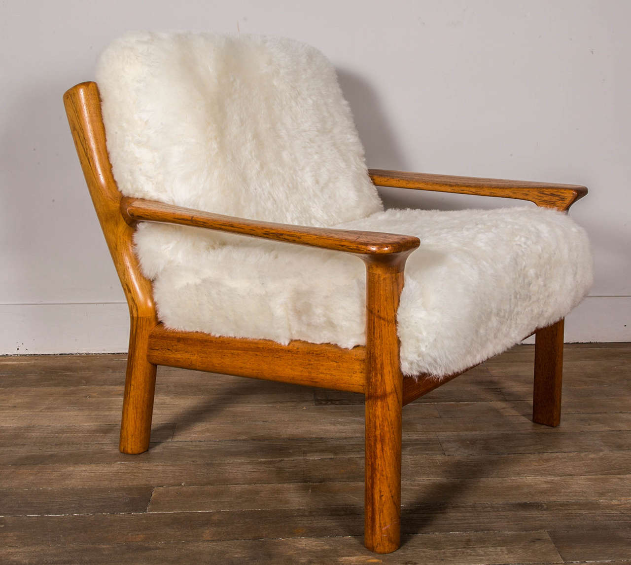 A pair of teak lounge chairs re-upholstered in sheep skin. 
Glostrup Mobelfabrik ( labelled) 
Denmark,
Circa 1970.