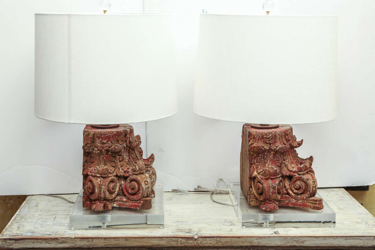 Lamp fashioned from red painted carved capital. Early 19th century hand carved capital with traces of original polychrome finish. Mounted on Lucite base. Newly wired as custom table lamp for use within the USA using all UL listed parts. Sold with a