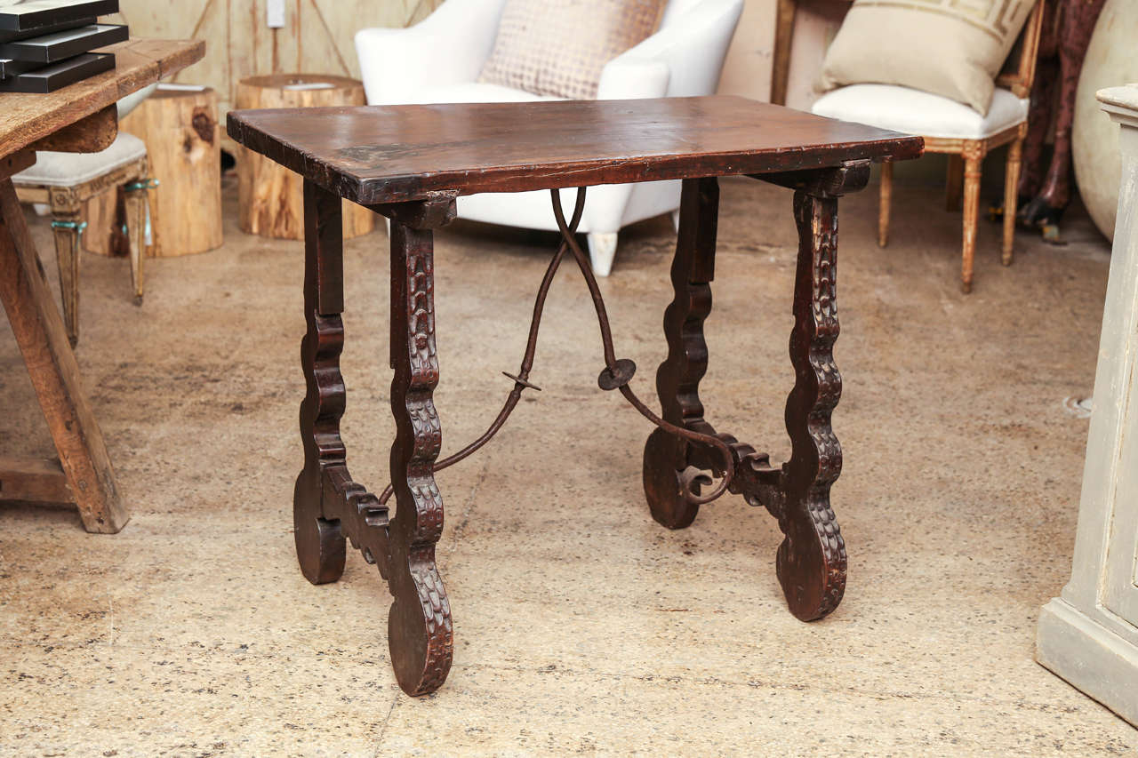 Small Spanish table in walnut with carved legs and iron stretcher.