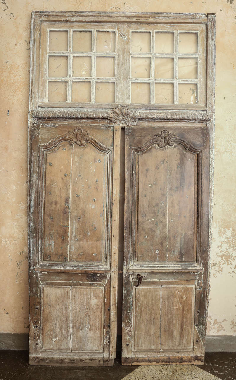 Large pair of transomed Louis XV doors: Régence period exterior doors, hand carved in oak with original transom. Dated to the first half of the 18th century. These doors and transom originally belonged to a home in Paris. They include original, or