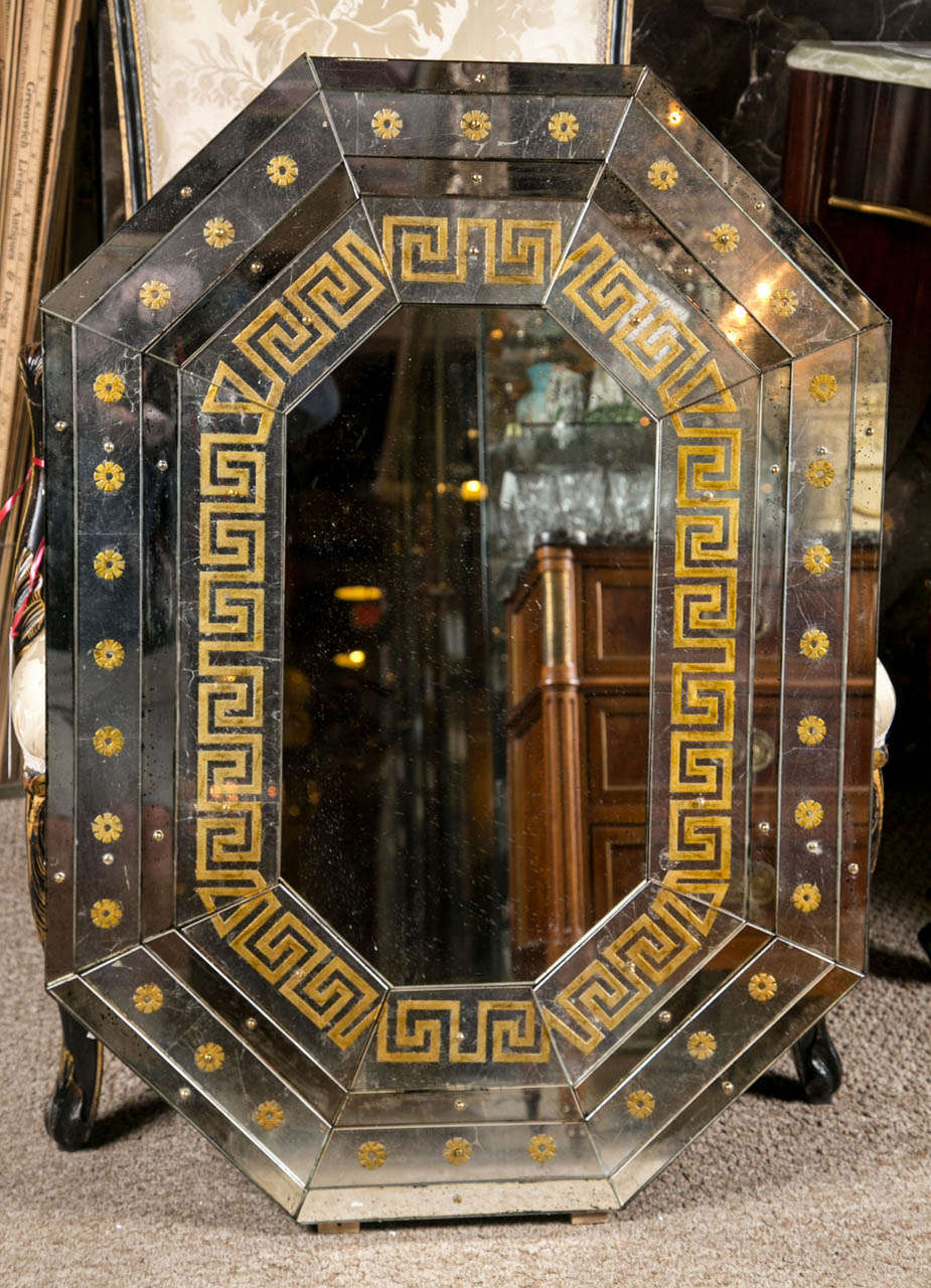 Pair of Maison Jansen Octoganal Mirrors. Each Verne eglomise mirror with a Greek key design gilt gold inlay having a border of rosettes. The overall distressed mirror appears to be made of 32 hand cut and designed pieces. Set of a solid wood backing.