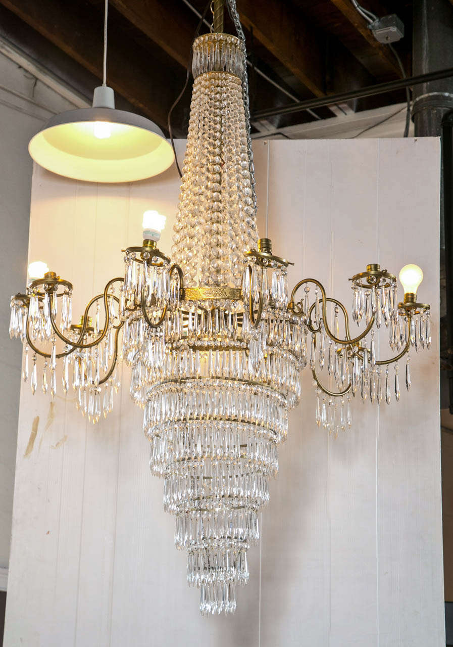 A Palacial Crystal and Bronze Tear Drop Chandelier. A crystal swag form upper section with a group of eight levels of crystal in a graduating design. The outer section of S shaped bent arms having ten lights.