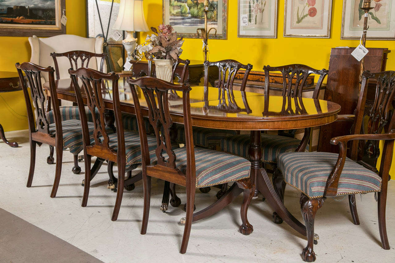 An English Triple Pedestal Banded Mahogany Dining Table. This tilting three pedestal dining table having recently been refinished has a mahogany flaming top with satinwood banding sitting on three pedestal all of which tilt for easy storage and