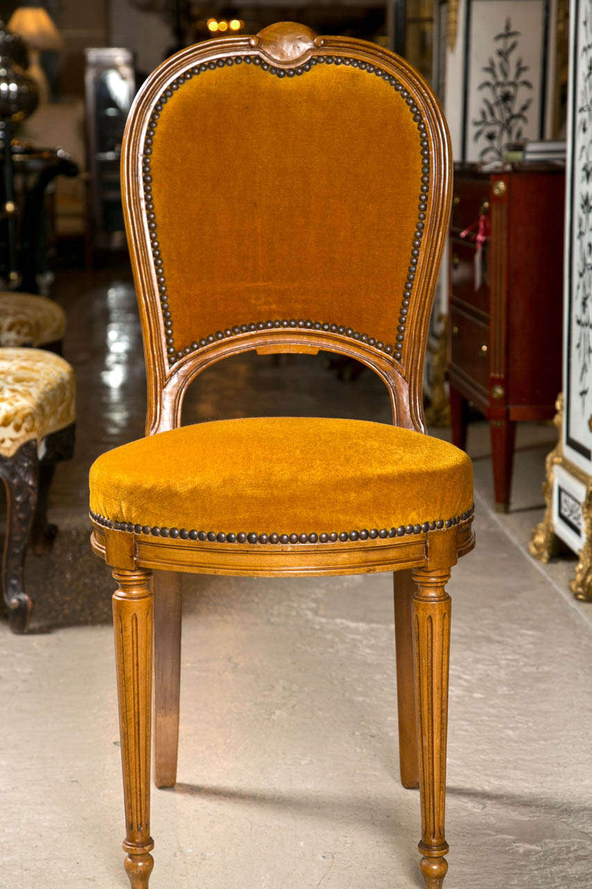 A finely constructed set of two Louis XVI style dining chairs by Maison Jansen. The tapering reeded legs supporting an apron with four box corners. The arch and curved back with velour tacked fabric, by Maison Jansen.