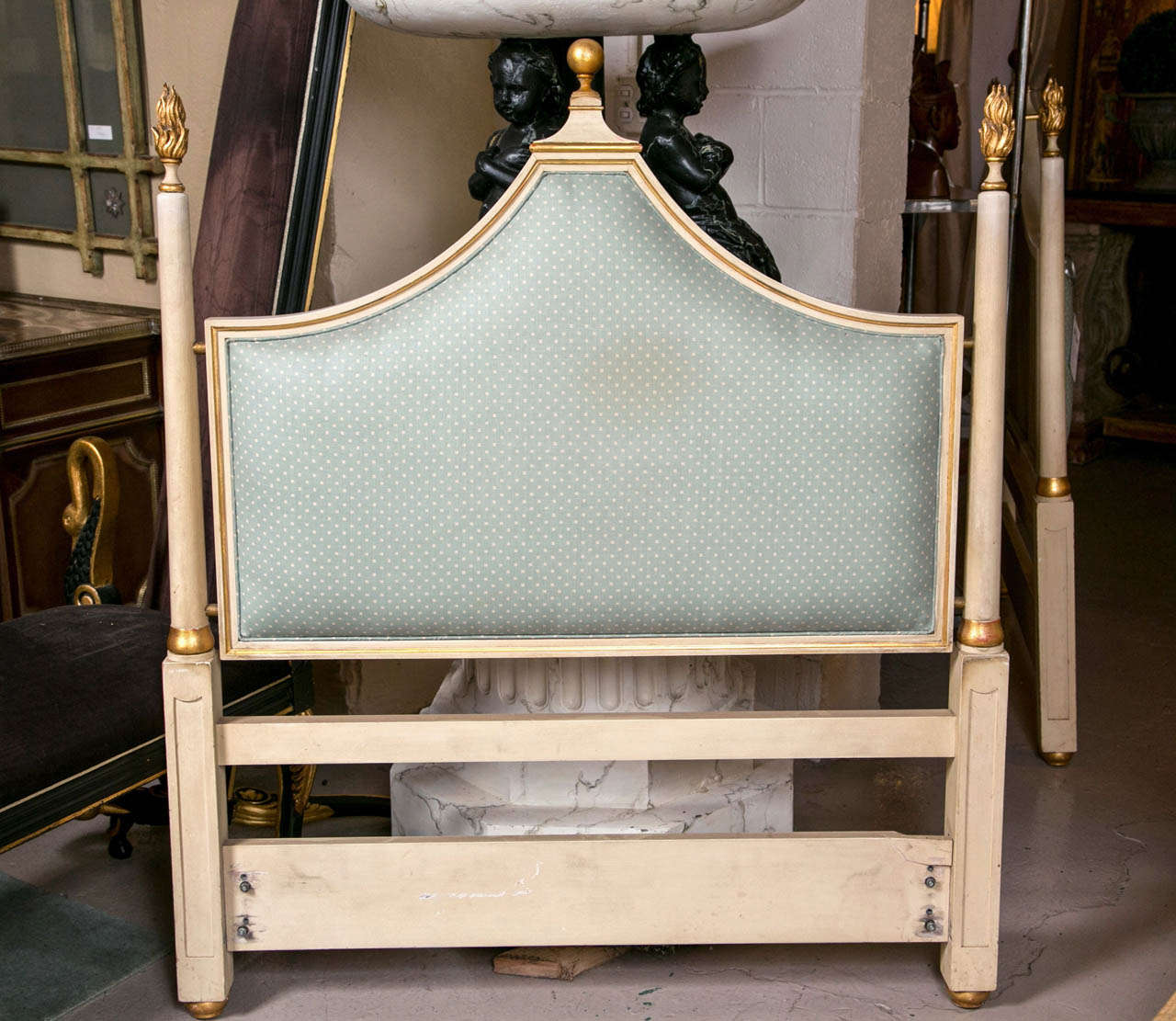 A pair of finely carved and painted twin size headboards with gilt gold hi lights. Each with a square bottom pillar frame leading to a circular pole with gilt gold bottom and terminating in a gilt gold torch flame. The nicely upholstered backs frame