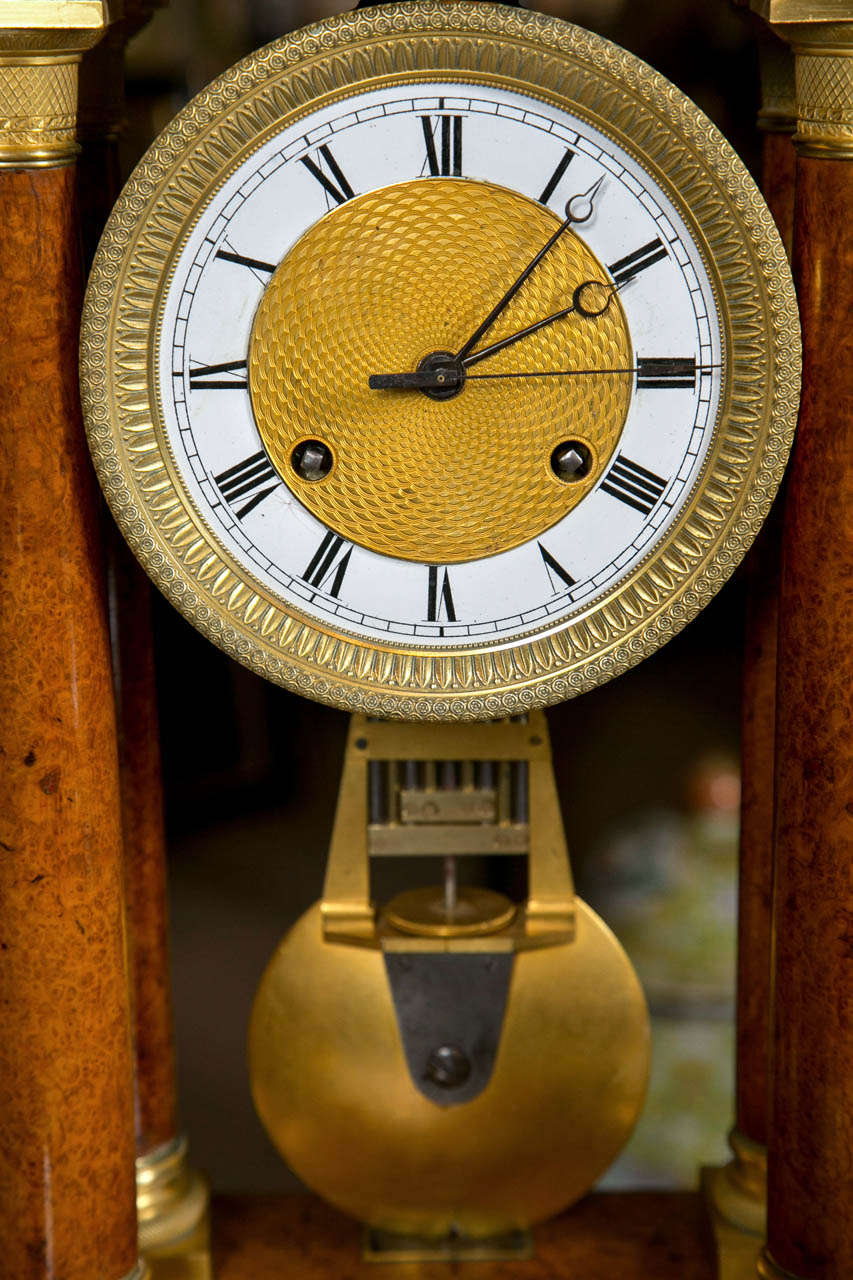 A French Empire pinwheel portico clock with figured amboyna wood. Signed Rieussec, Horlogier du Roi.