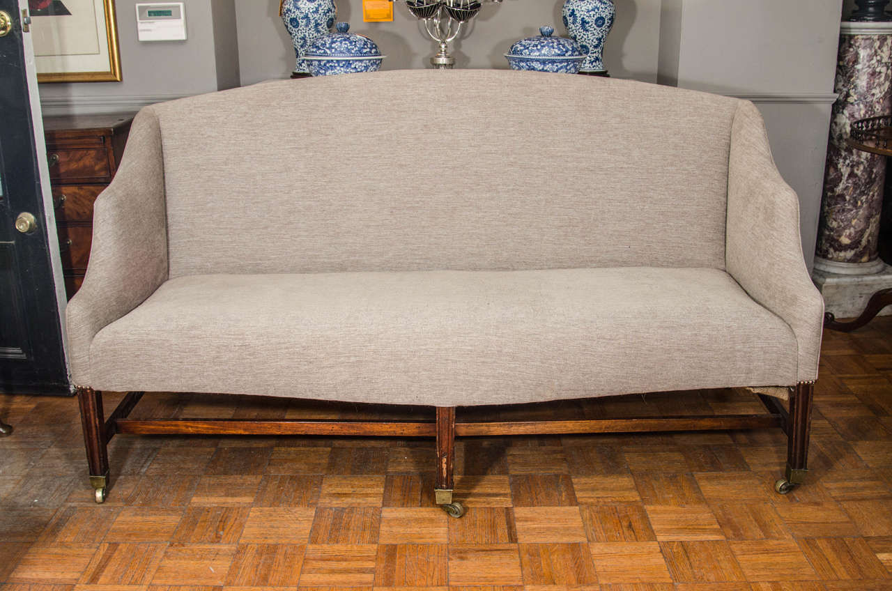 Hepplewhite sofa. On six tapered legs with spade feet, connected by stretchers and with original casters.