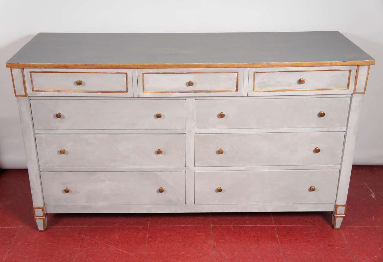 Classical commode painted French gray with gilt trim and brass knobs, the dresser holds quantities of belongings.  All nine drawers have dovetail construction and slide easily.

Keywords:  Louis XVI style chest of drawers, Gustavian style chest of