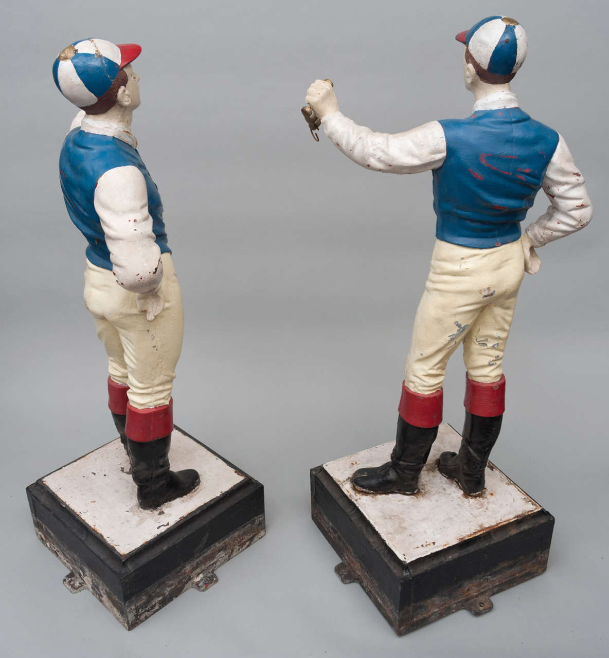 A rare pair of late C19th American cast iron jockey tethering posts,
the jockeys dressed in silks standing with one hand holding a ring, on a square base with four fixing lugs.