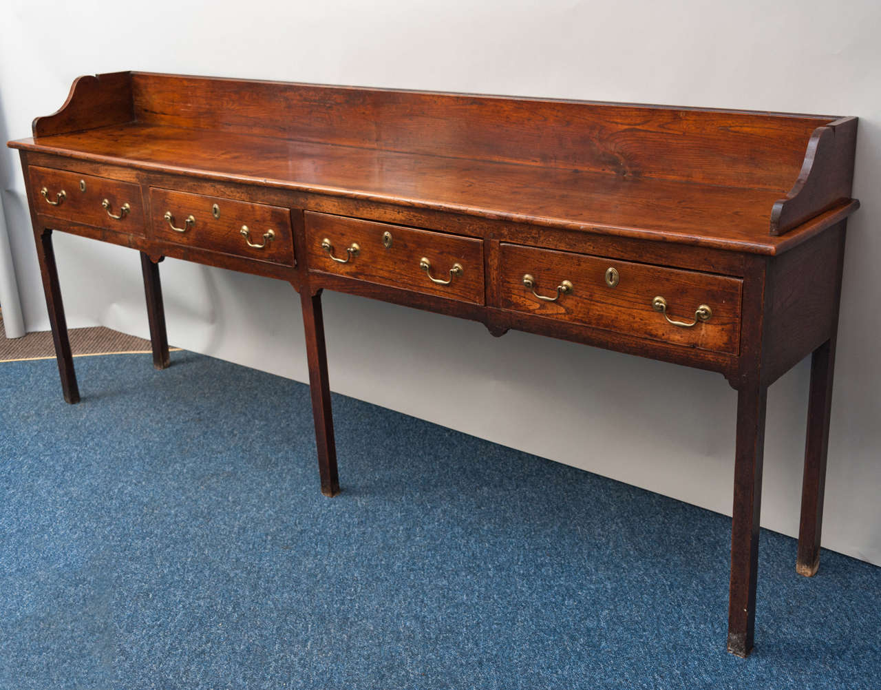 A good and unusual George III elm dresser base of impressive proportions with 4 drawers with original swan neck handles; raised on square chamfered legs; with good colour and patination.

Height to 35
