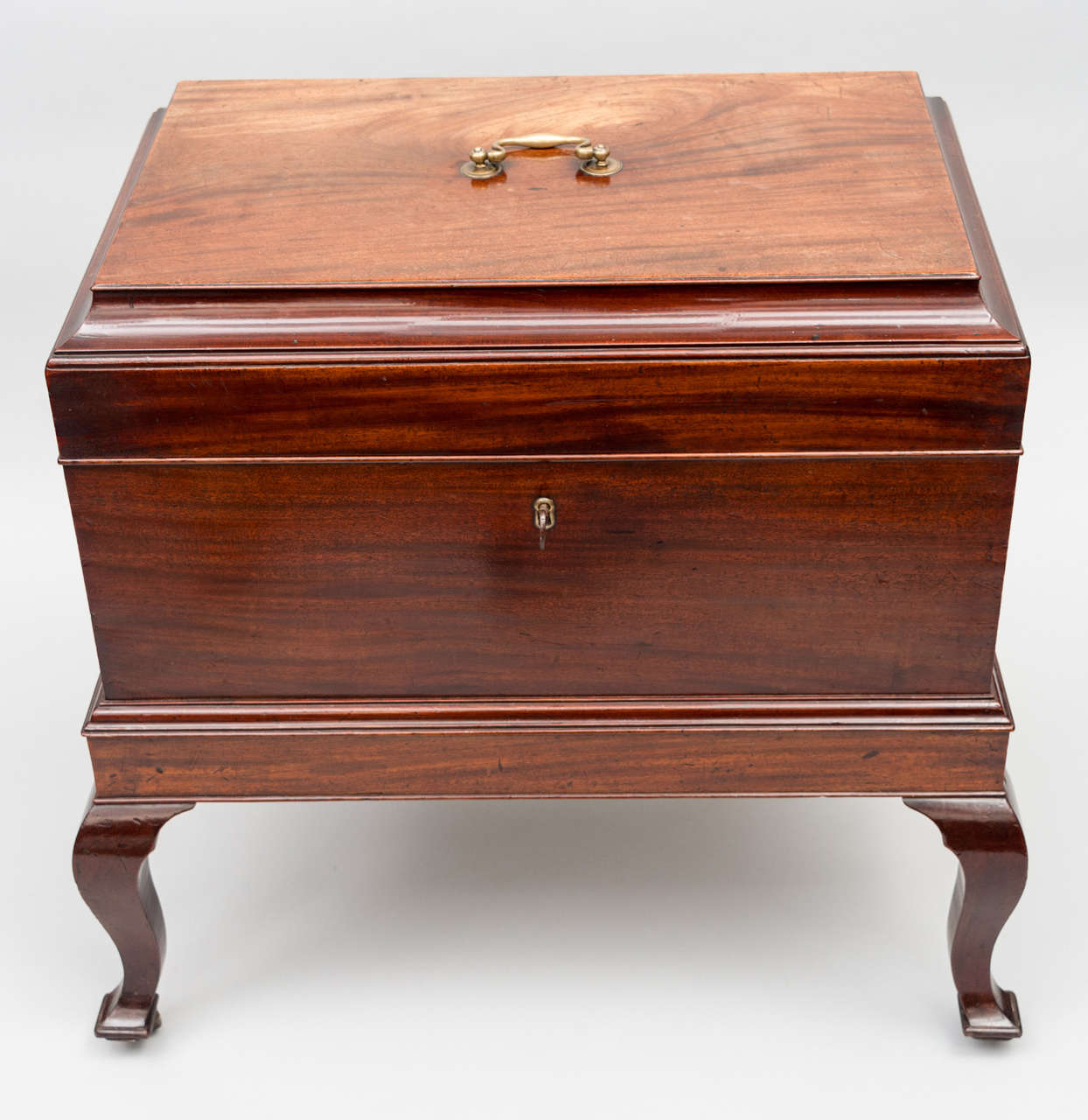 A rare, handsome, Georgian mahogany wine cooler of very unusual form. The caddy shaped top with original lifting handle, the flat sides with original carrying handles; with a moulded frieze on square section cabriole legs; with original brass