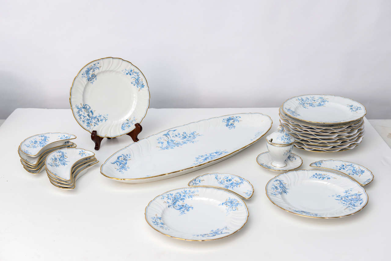 Full set of fine quality porcelain. This elegant set has the large centerpiece, lidded sauce tureen, platters for fish course and crescent shaped bone dishes. Original gold edging very much intact. Service has a very light feel to it due to the bone