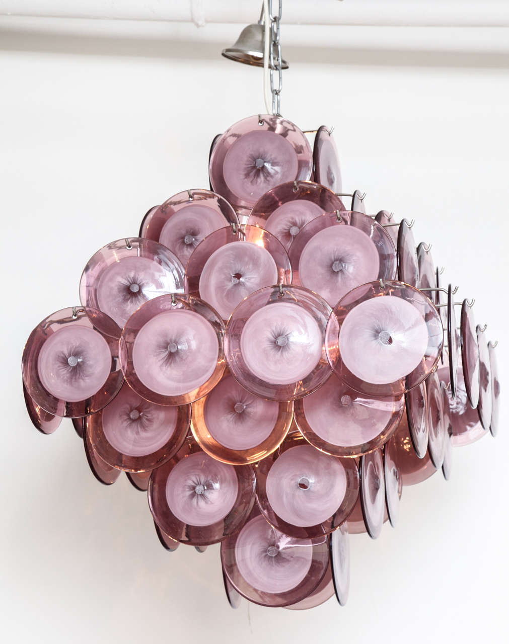 This double-sided pyramid disc chandelier is comprised of individually handblown purple or amethyst and white colored murano glass suspended from a chrome frame.  The color of the discs vary between amethyst, pink, lavender and light purple hues.