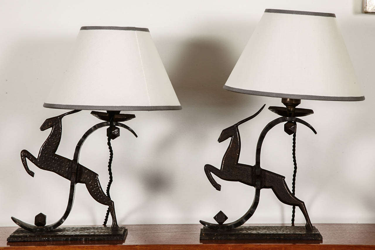 Pair of hammered wrought iron candlesticks mounted in table lamps and representing two drawned up antelopes (one more elevated than the other) mounted on a rectangular tiered base. Engraved stamp 'Zadounaisky'. Art Deco, circa 1925. Wired for