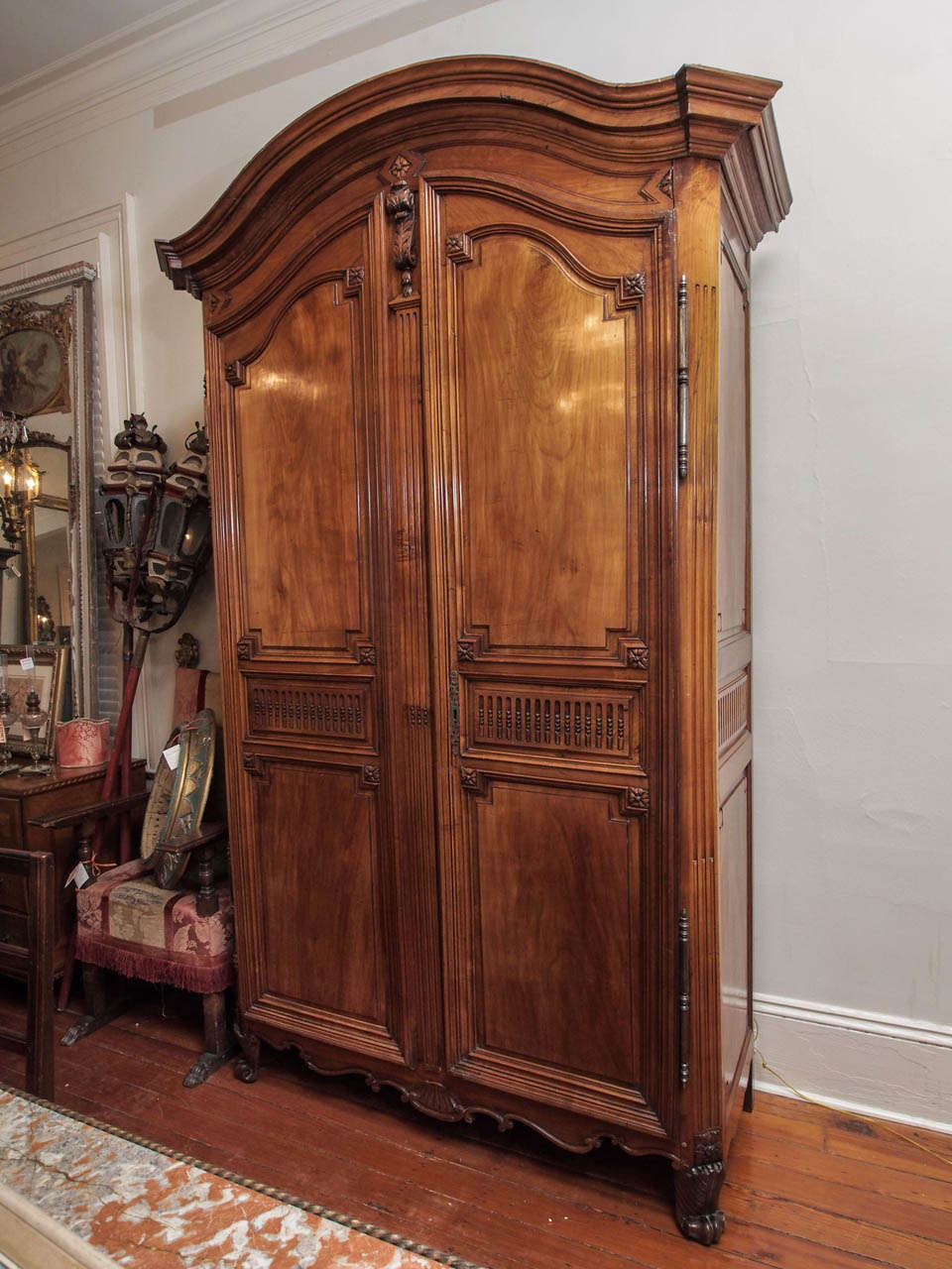 A Louis XVI armoire, from Bordeaux, having an arched and deeply molded cornice over a frieze with carved rosette atop a bracket, the doors conforming to the cornice, and having central panels with asparagus fluting. The canted rails and center faux