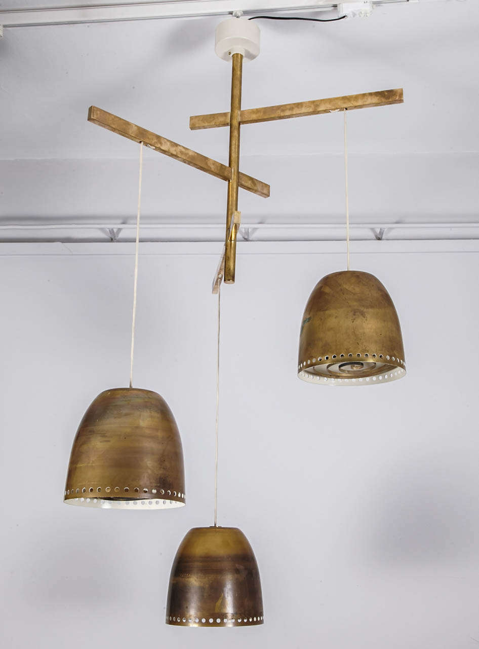 An elegant brass ceiling fixture
Finnish, 1960's
Composed of 3 perforated brass pendants each with a spiral bulb shield on  a metal structure.
Adjustable Height
