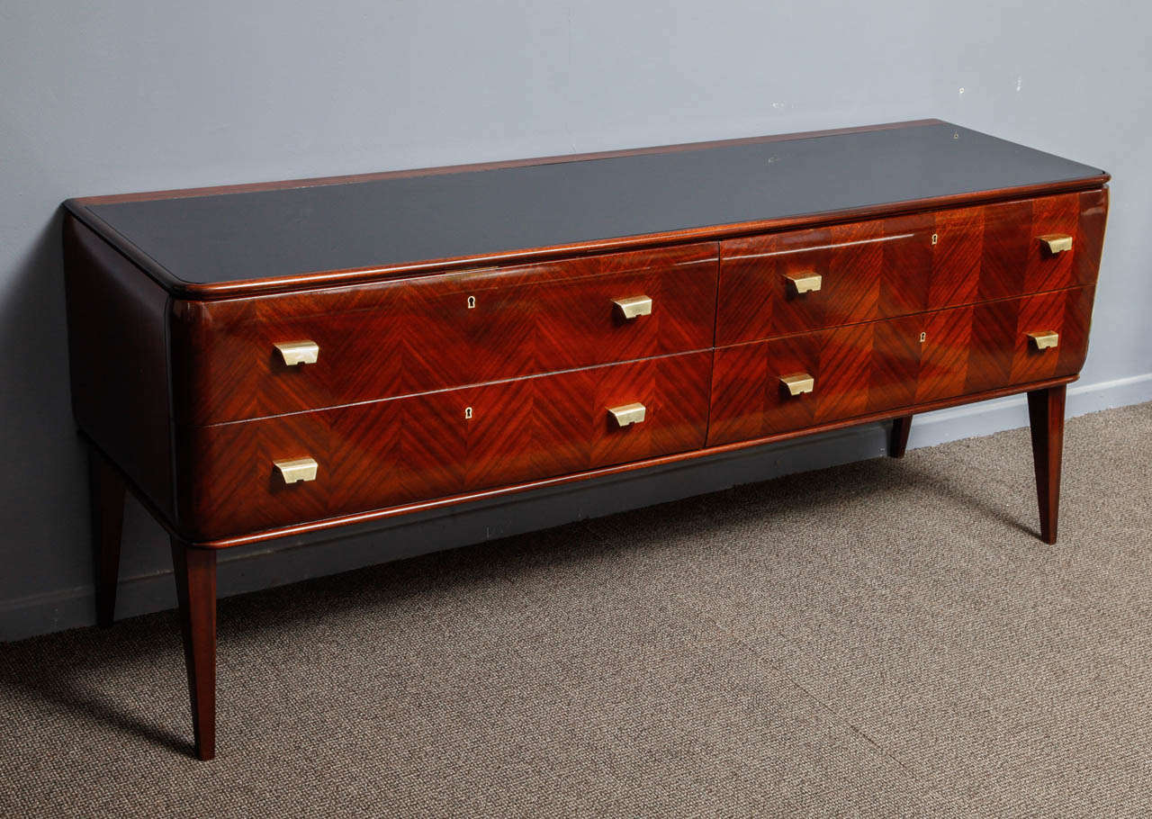 Italian origin Mahogany veneered four drawers chest of drawers,refinished with hand made French Polish. Brass hardware and black glass top. 
There' s a possibility to purchase it with a matching pair, please consult my store front for more
