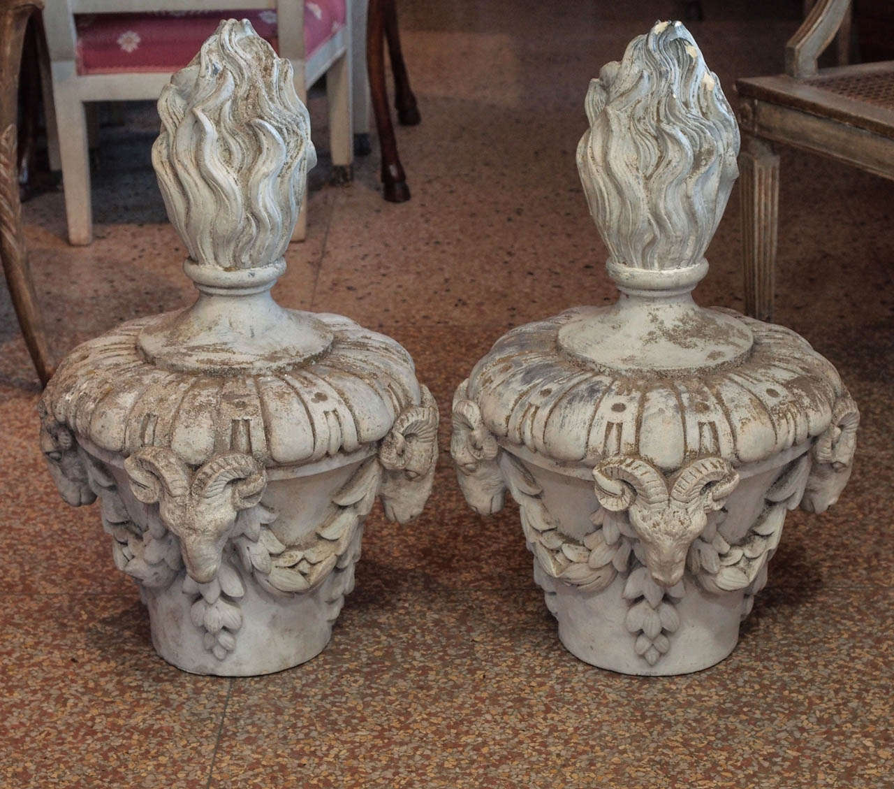 Pair of French gray patinated terra cotta finials having 4 ram's heads, leafy garlands and topped by a large flame.