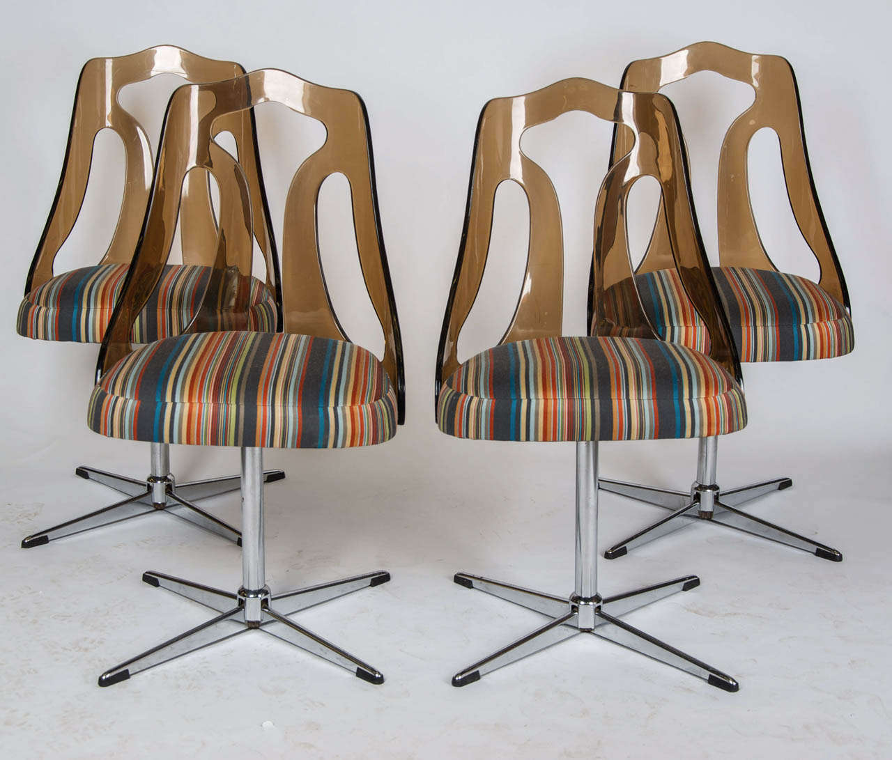 A set of four 1960's dining chairs with light brown open-form plastic backs set on a chrome base and newly recovered in Paul Smith fabric.
