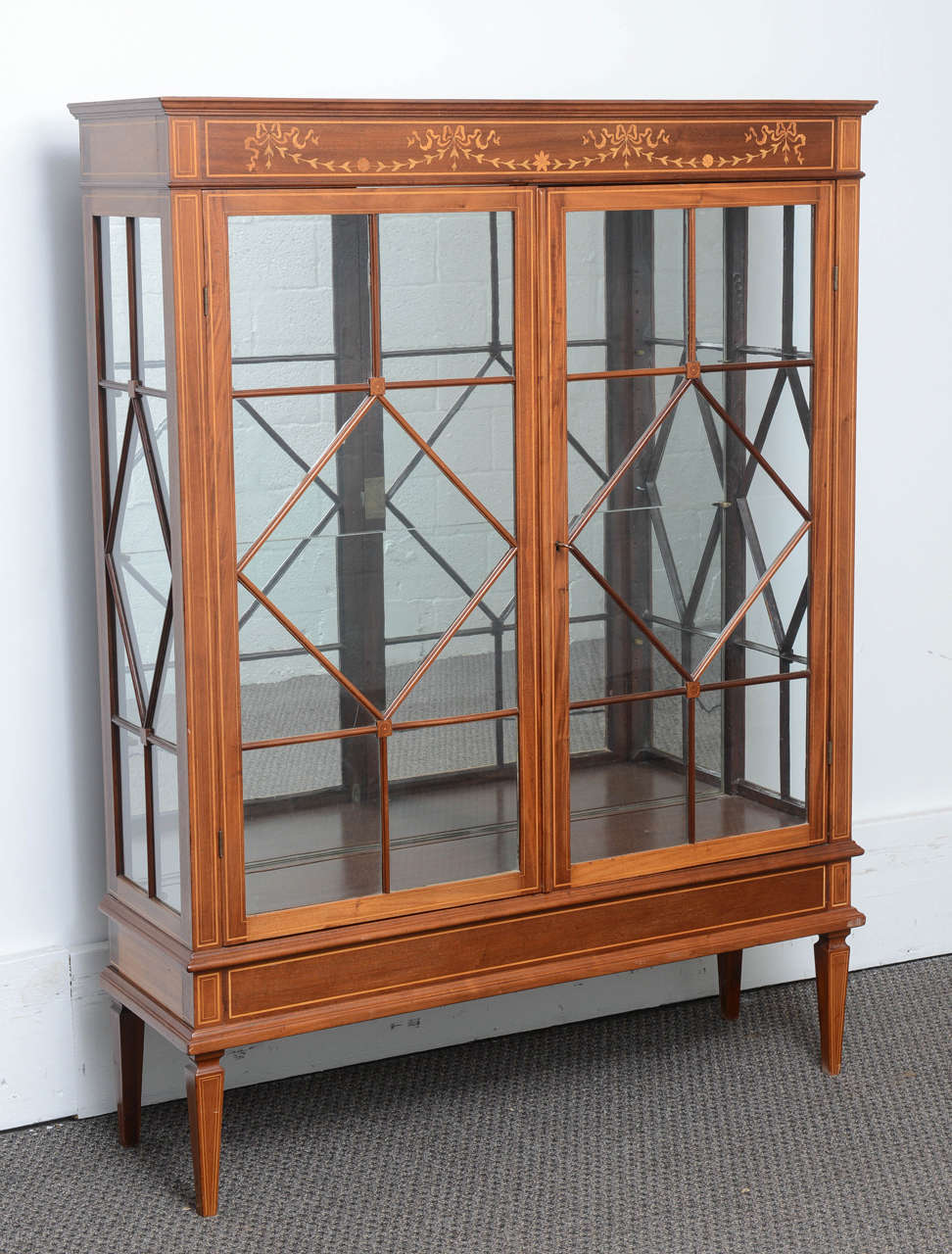 This is a superb solid mahogany display cabinet made in England, circa 1890.
There are two glass doors with wood beading to the front, it smothered in satinwood marquetry inlay and in excellent condition.
It sits on square tapered legs to either