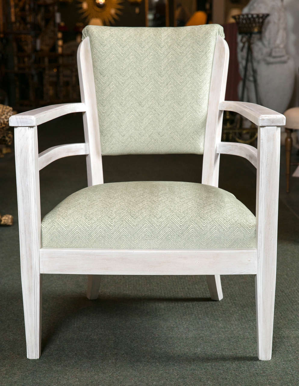 A French armchair of pickled wood with upholstered back and slip seat having open arms and tapered front legs.