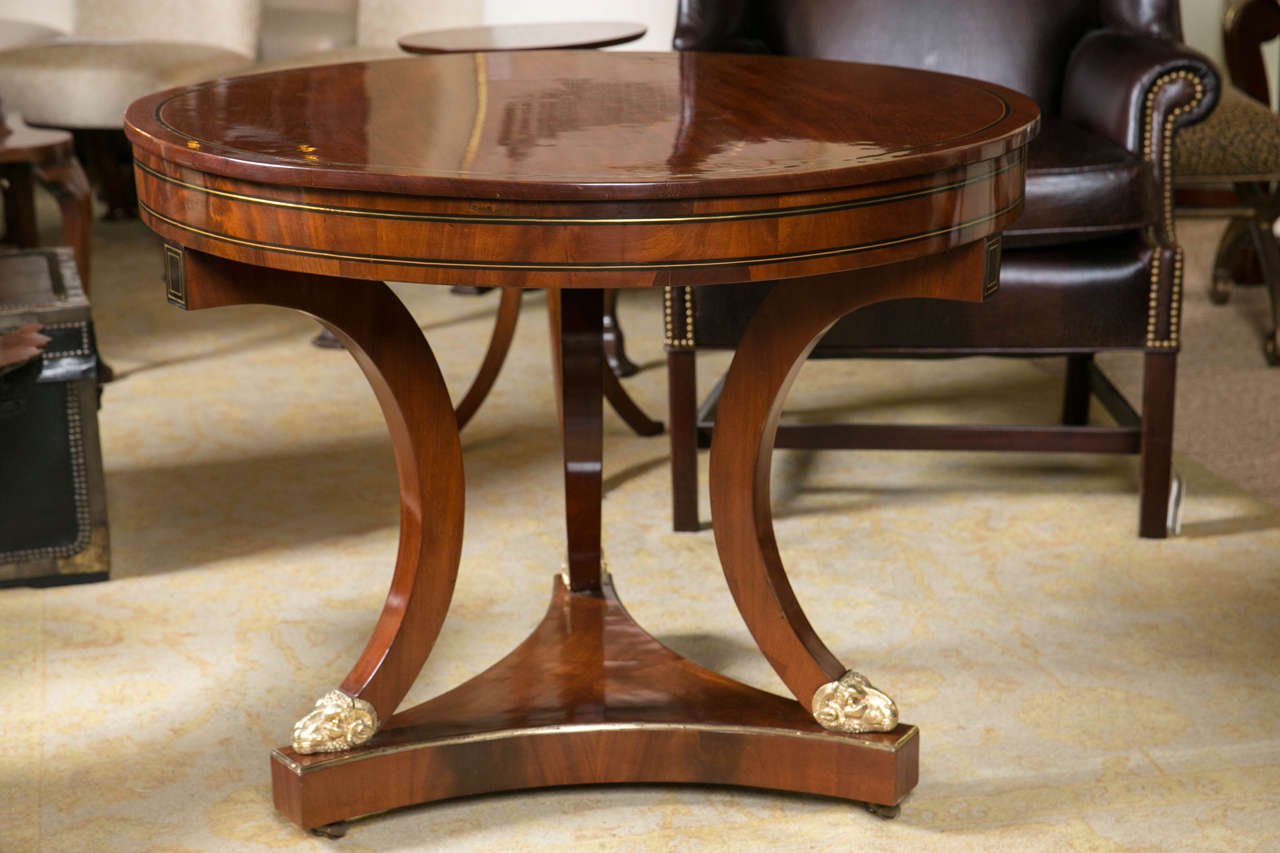 An interesting mahogany, ebonized, gueridon table with brass and satinwood stringing on a tripod base, terminating in ram's heads on a triangular base.
