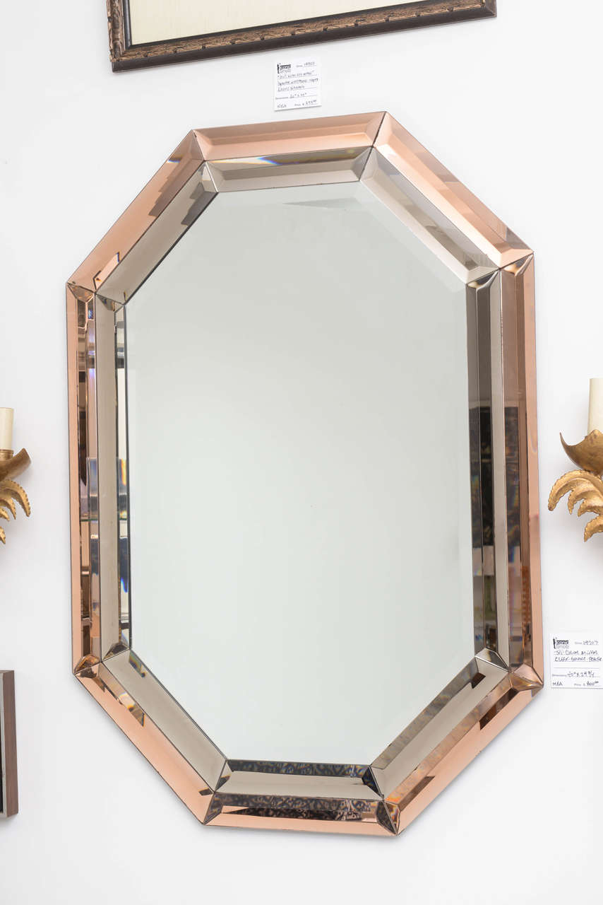This mirror was created in the 1970s and definitely creates a mood of glamour and elegance.

The central mirror is clear/silver and the border is comprised of a smokey grey and peach/copper.

There are minor inclusions on some sections of the