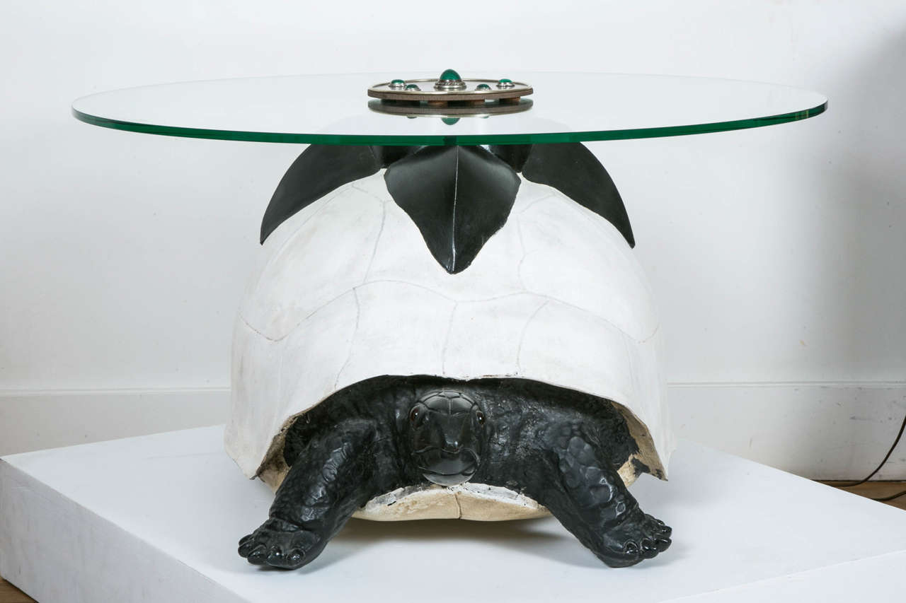 Black and white tortoise coffee table with a circular glass top, 1970-80, by Anthony Redmile (1945-).
Patinated resin tortoise four upper leaves, glass eyes. Gilt and brown brass circular upper plate with malachite cabochons.
Signed.
Tortoise