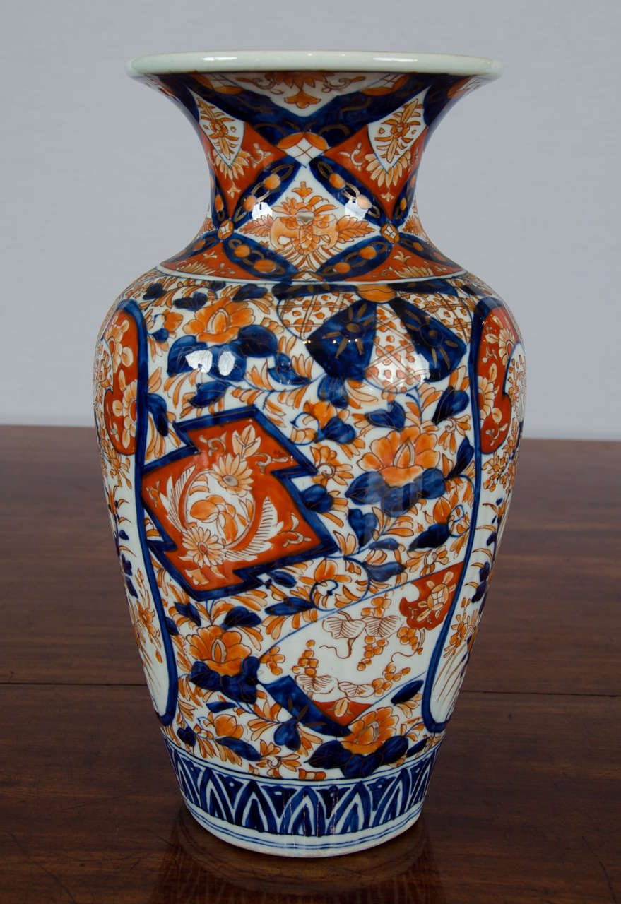 This splendid tall Japanese Imari vase features a very flared neck with a traditional hand-painted all-over pattern of birds and sprays of flora. The vase is unsigned but in lovely condition, and has a dainty bit of detailing around the inside top