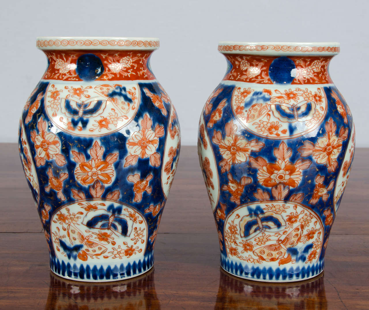 These delicate pair of Japanese Imari vases has a profuse and busy design of floras and butterflies in a Classic bulb shape.
