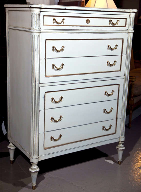 Solid wood six-drawer Louis XVI style chest. The central drawer structure flanked by a set of reeded column sides. White wash finish with gilt hi lights, on bronze sabots with brass pulls. Maison Jansen stamped.