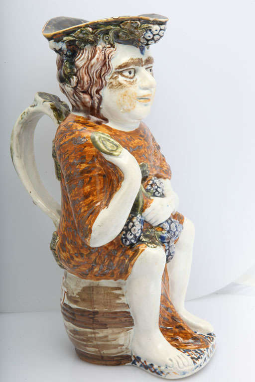 An important English pearlware pottery Bacchus toby jug decorated in underglaze Pratt colors, with 