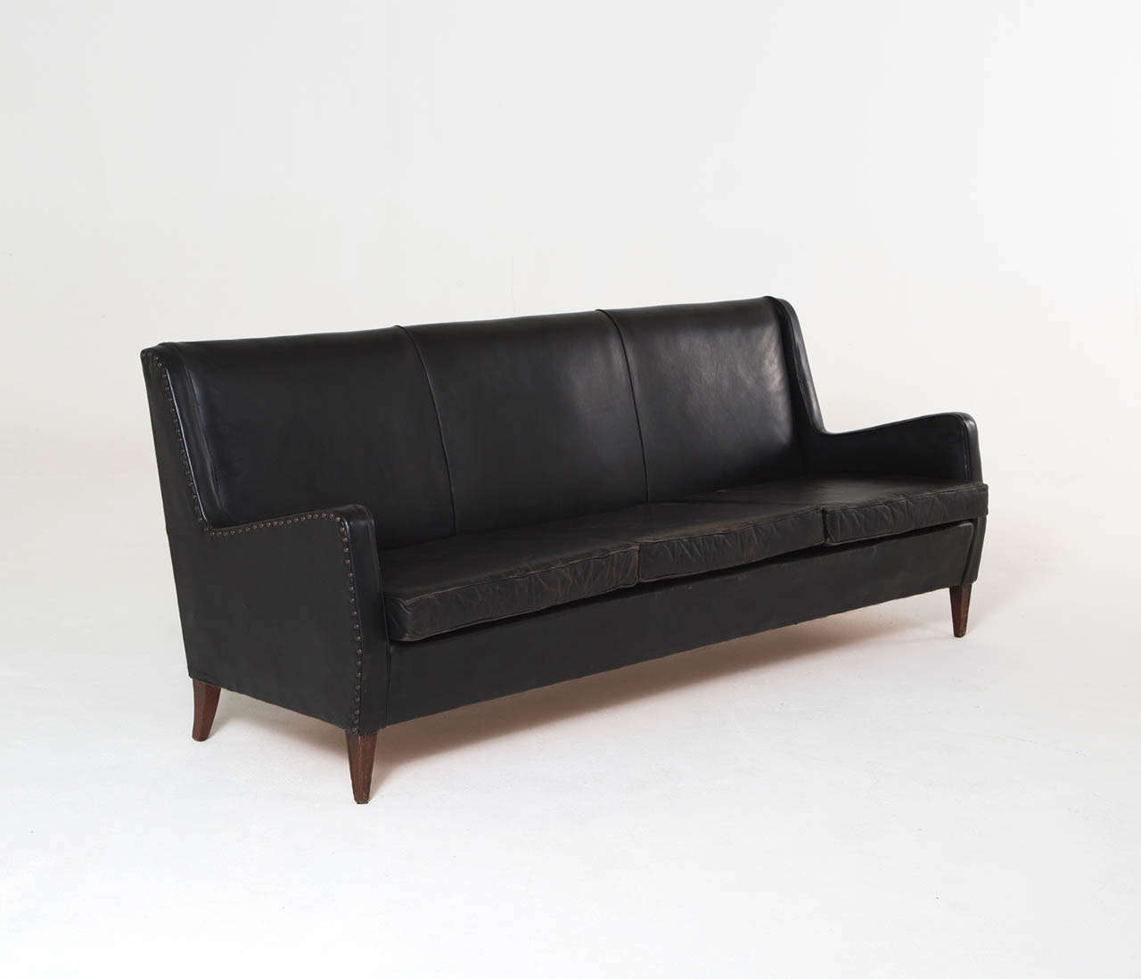An elegant designed three-seater sofa in original leather with gorgeous patina and brass nails in the style of Frits Henningsen, Denmark circa 1950. The legs are made of dark stained oak. 

Completely original and checked on every single detail to