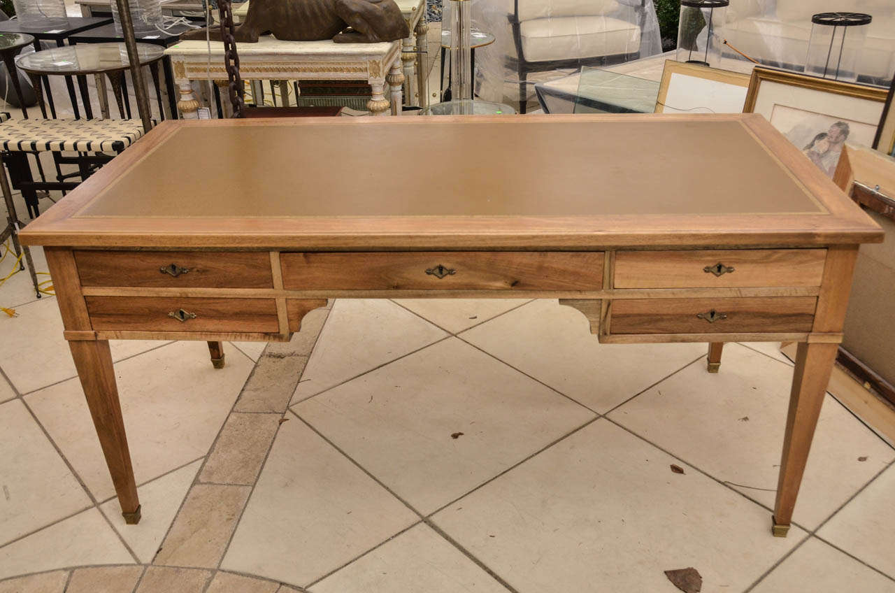 A fine French Andre Arbus style desk with an inset leather top. The desk has five drawers supported on tapered legs with bronze sabots
